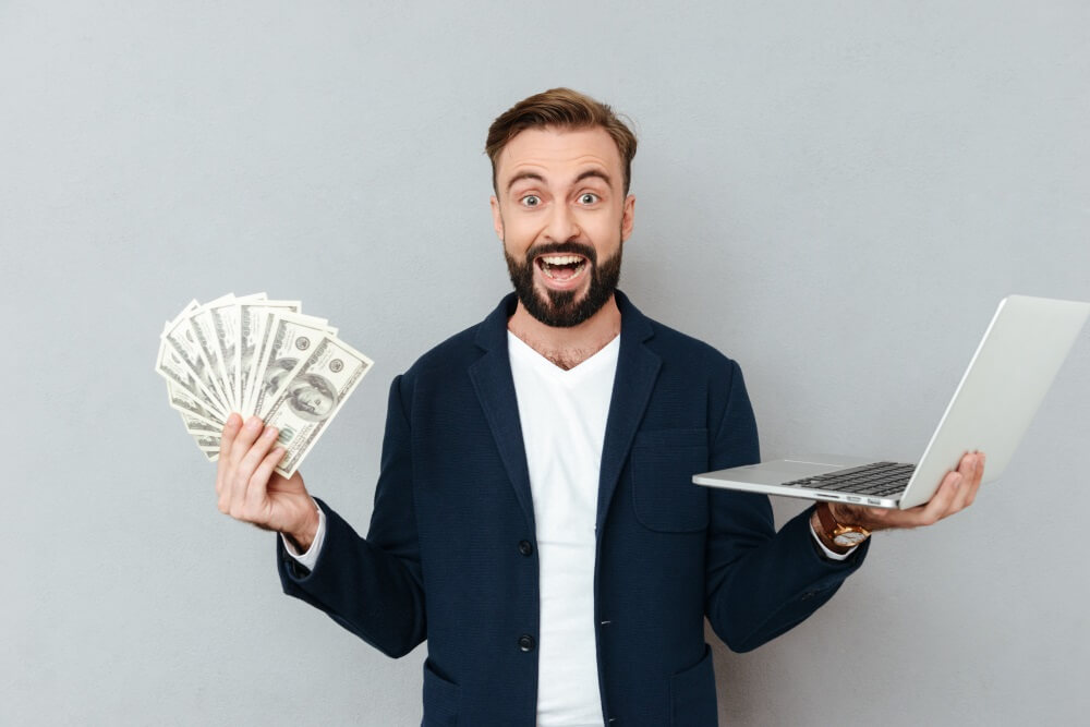 excited boy hold money and laptop