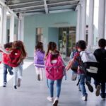 Elementary school kids run from camera in school corridor