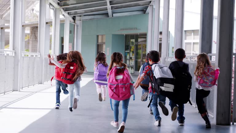 Elementary school kids run from camera in school corridor